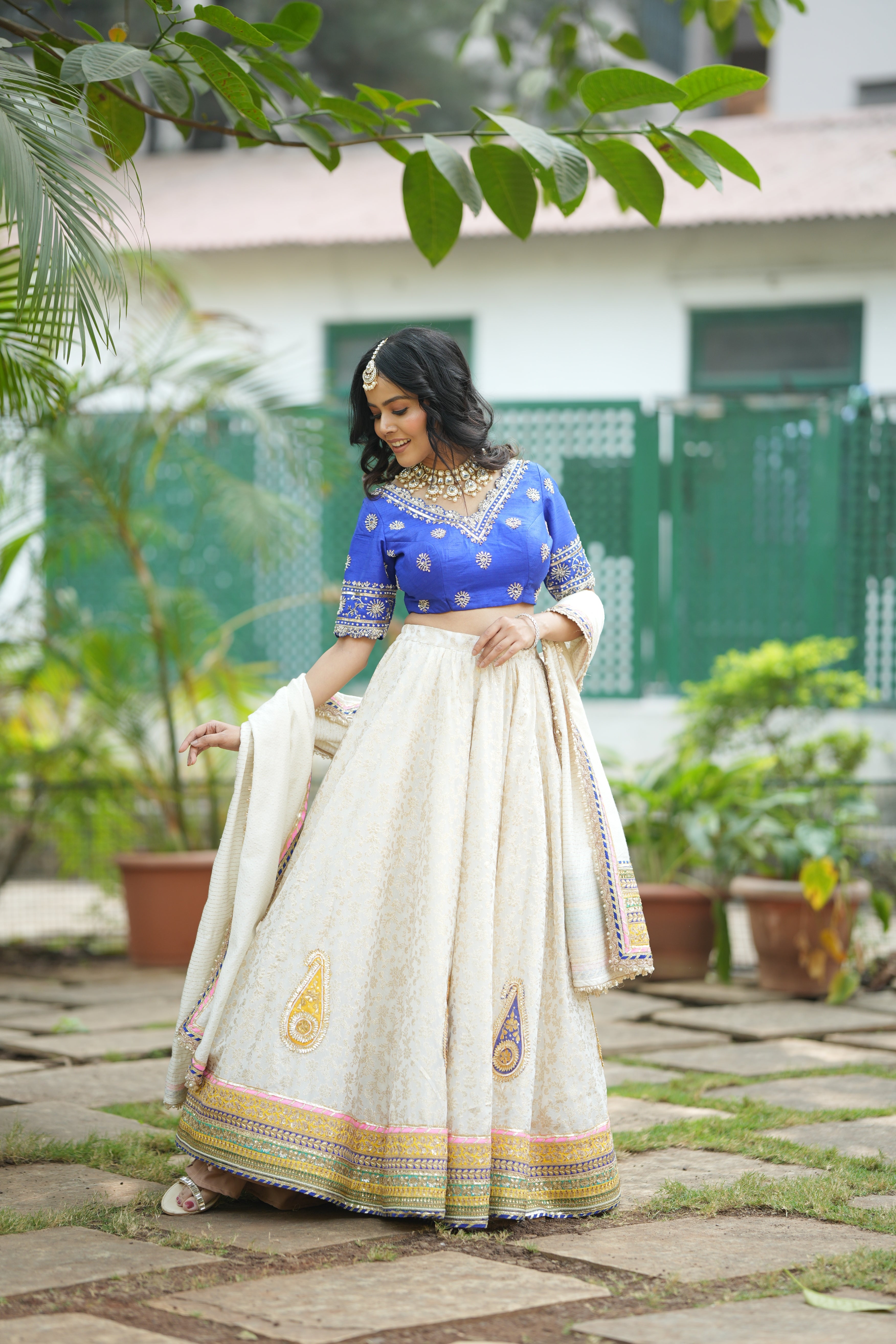 Model wearing royal weave Banarasi designer lehenga set with dupatta and blue raw silk blouse.