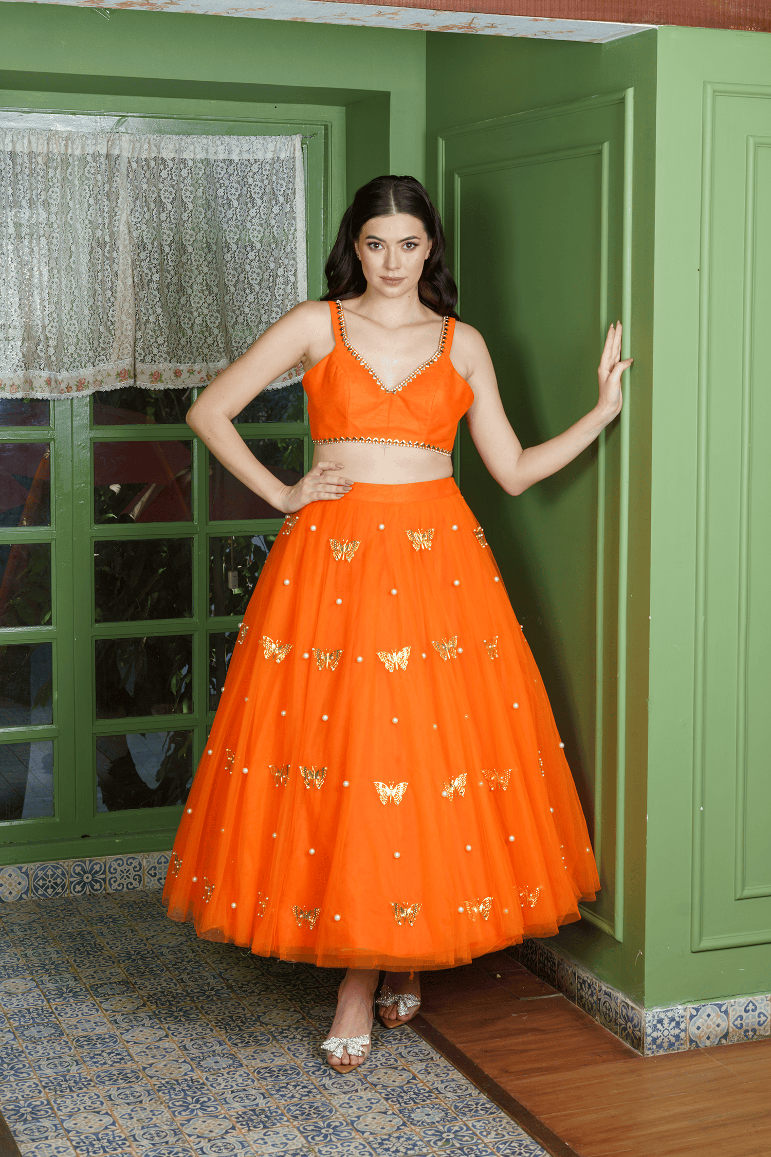Woman wearing orange lehenga choli with butterfly motifs