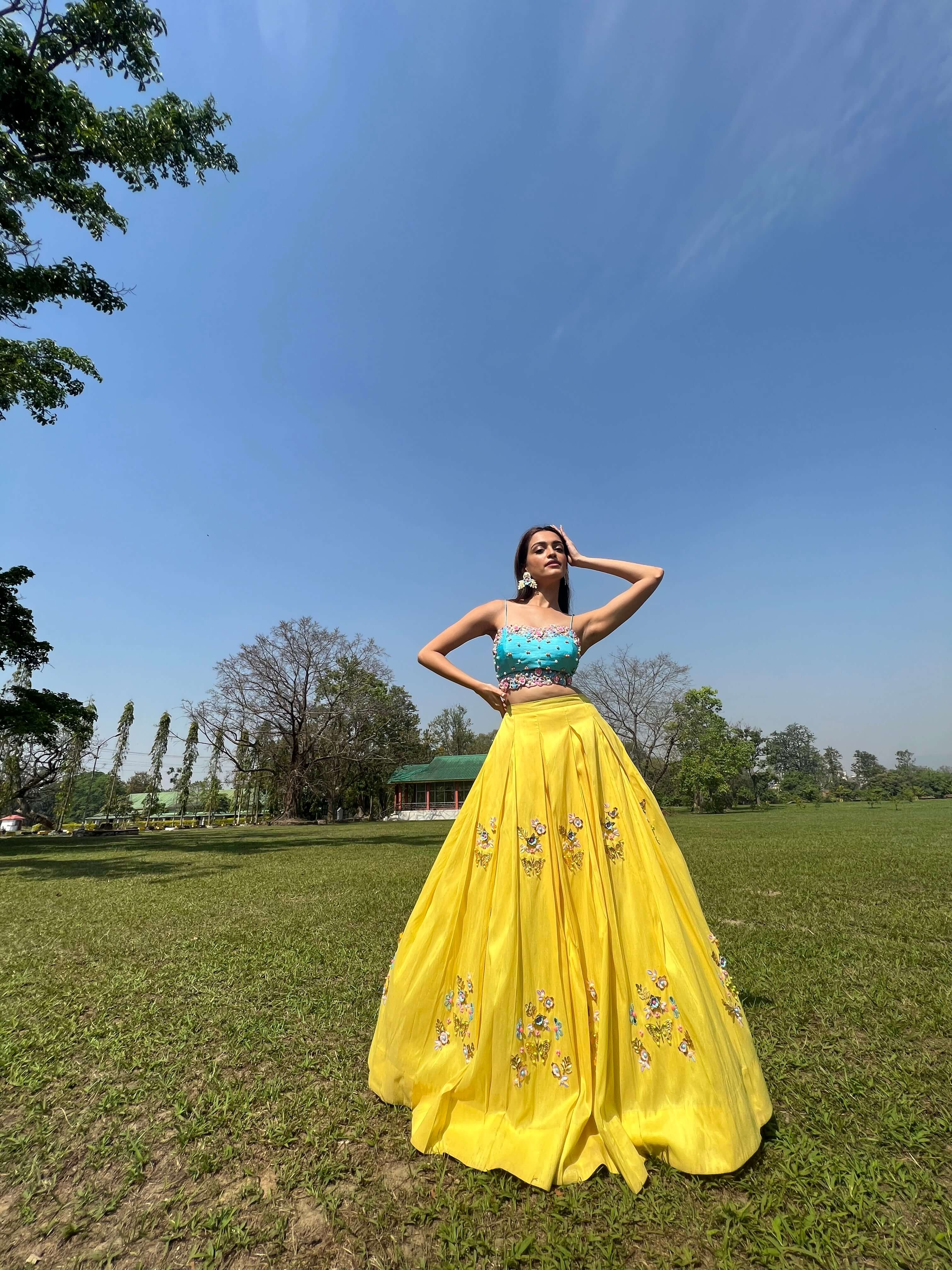Yellow silk crop top lehenga for wedding with floral embroidery and turquoise blouse.