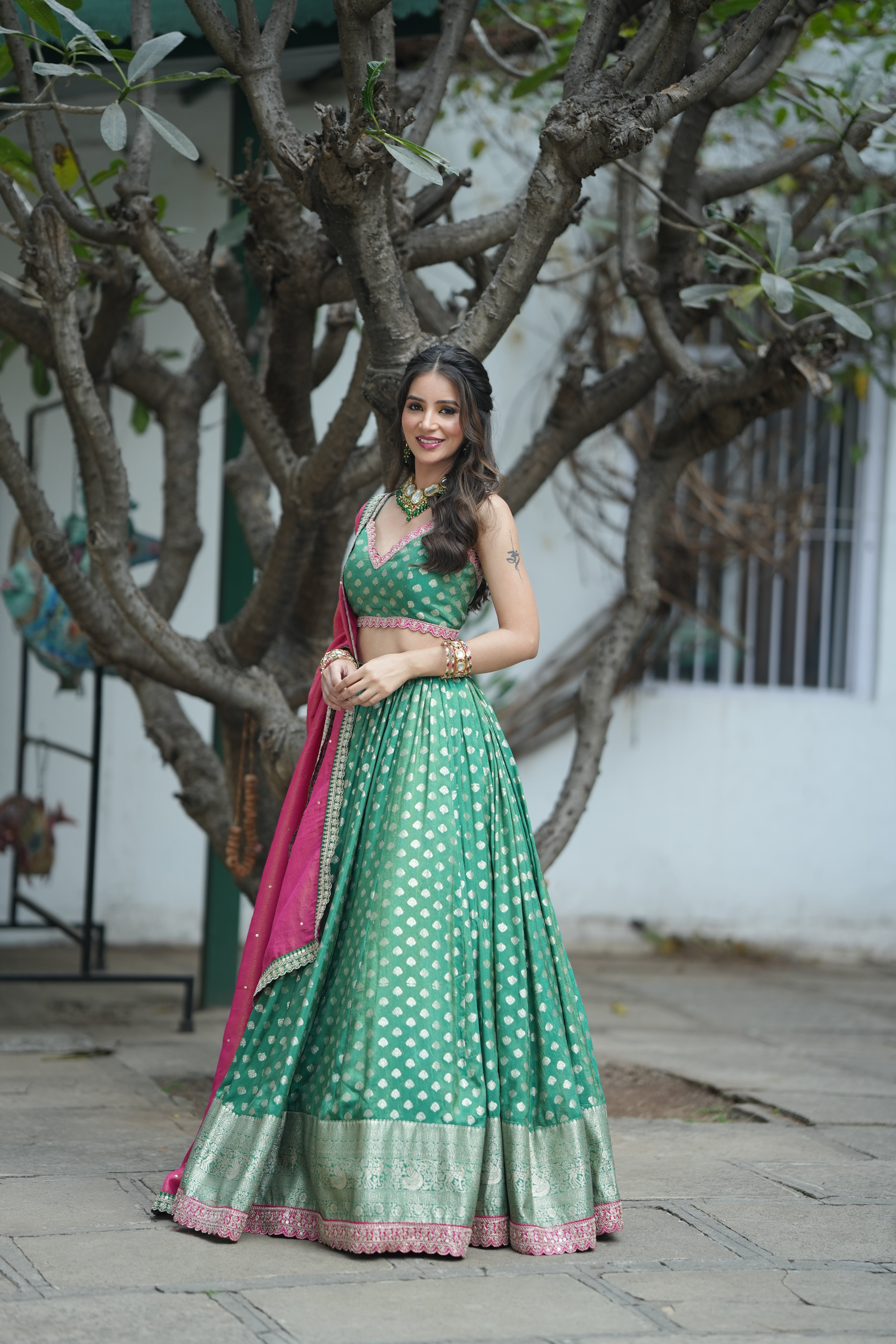 Emerald Opulence Green Banarasi Lehenga with an elegant pink dupatta draped over the shoulders.