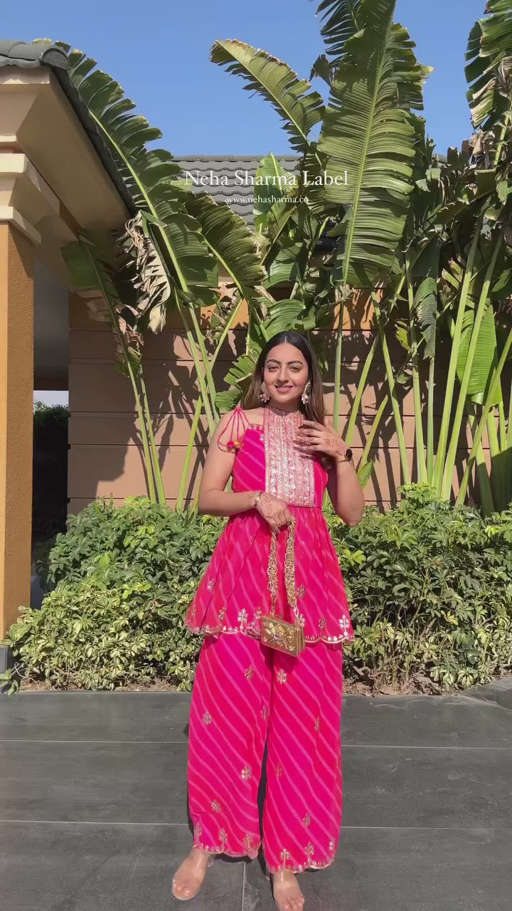 Woman wearing festive fuchsia Lehariya kurta set with sleeveless peplum and palazzo pants