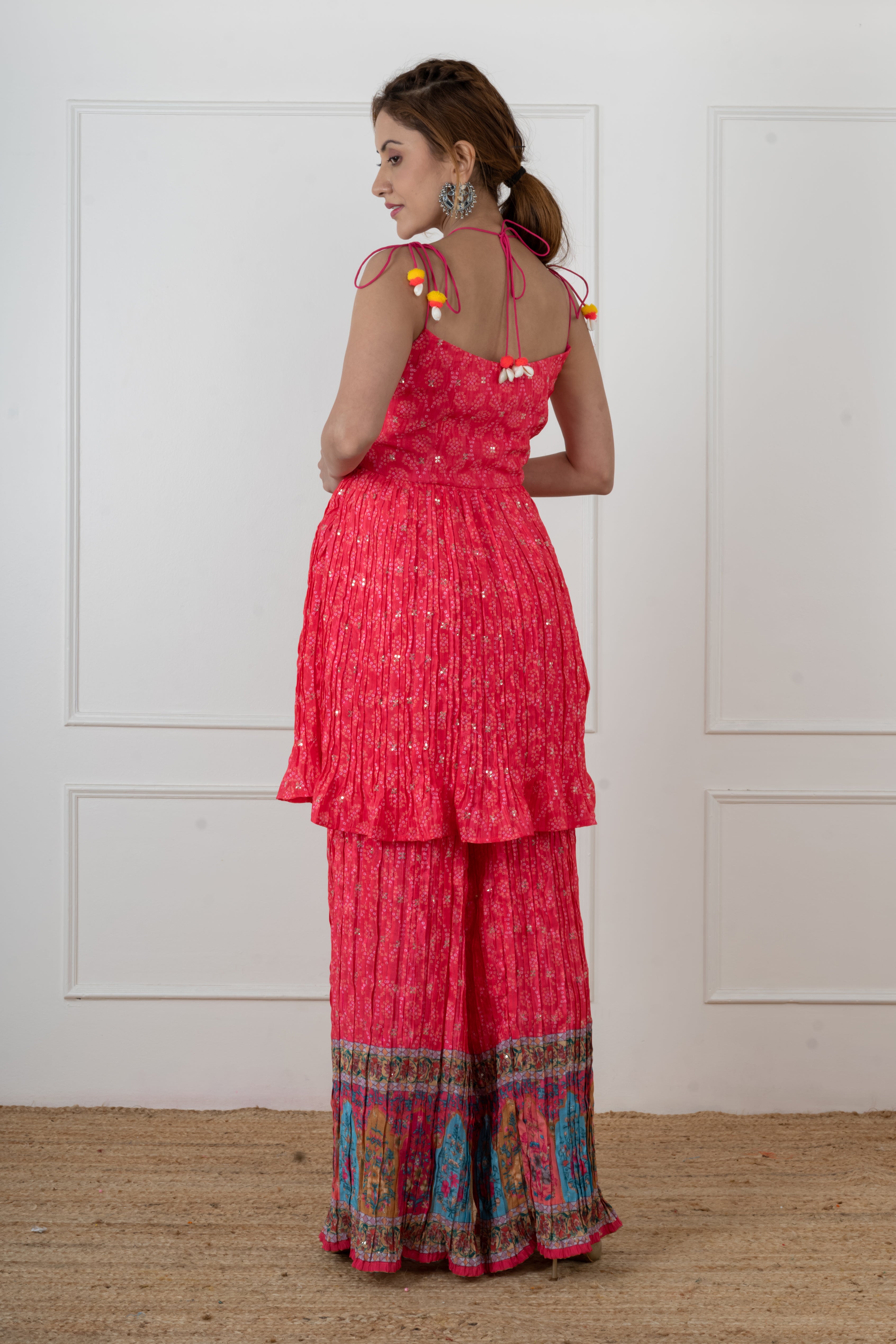 Woman wearing pink Bandhani mirror work kurta palazzo set, sleeveless halter neck
